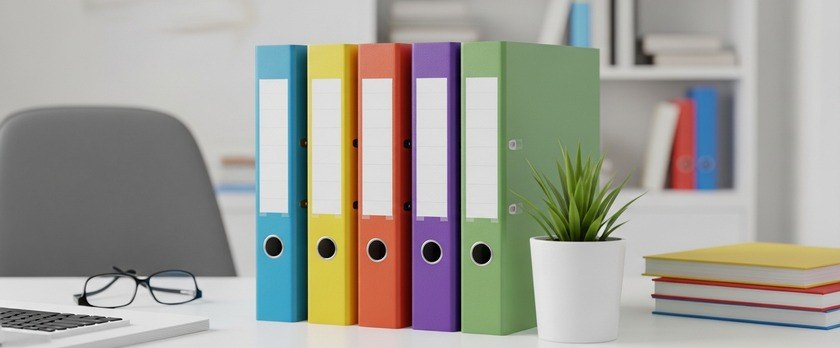 Hình ảnh bàn làm việc sáng sủa với các tập tài liệu trống được sắp xếp theo màu sắc. Hình ảnh tượng trưng cho việc sắp xếp và tiến hành chuẩn bị hồ sơ gia hạn visa Quản trị/quản lý.