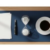 砂時計と書類、観葉植物を並べた明るい机の俯瞰イメージ。配偶者ビザの審査期間を落ち着いて待つことを象徴する記事アイキャッチ。