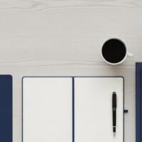 窓辺のデスクにノートと書類フォルダ、万年筆を並べた俯瞰イメージ。在留カードの紛失・盗難時の再交付手続きの準備を象徴。