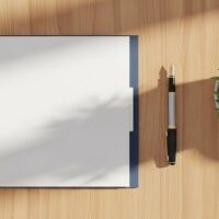 書類とペン、観葉植物を並べた明るい机の俯瞰イメージ。帰化申請の準備を象徴する記事のアイキャッチ。