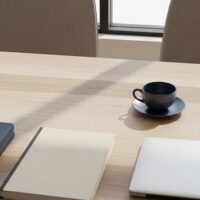 モダンなオフィスのテーブルにノートPCと書類フォルダを整然と並べた俯瞰イメージ。中小企業の外国人雇用の実務準備を象徴。