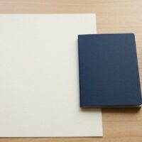 入国前結核スクリーニングで求められる結核非発病証明書の準備を象徴する、机に置かれた無地の証明書用紙と旅券大の冊子のイメージ