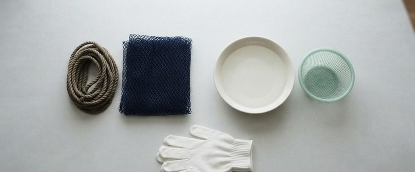 巻いたロープと漁網、水を張った浅い器と網かごを並べた俯瞰イメージ。特定技能・漁業分野の漁業と養殖業の2区分を象徴。