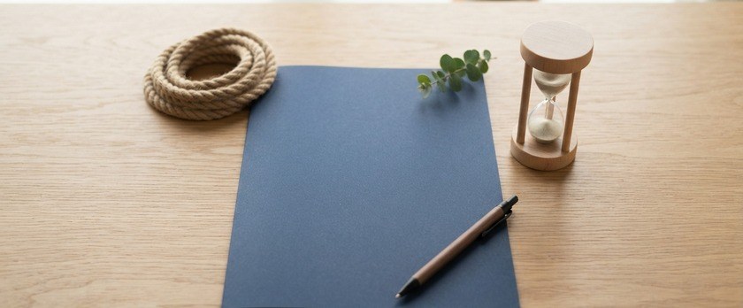 無地の書類フォルダと砂時計、巻いたロープを並べた俯瞰イメージ。漁業特定技能協議会への加入が申請より前に必要であることを象徴。