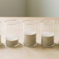 中身の量が異なる無地の容器を並べた俯瞰イメージ。特定技能の分野別の受入れ枠の残りを象徴。