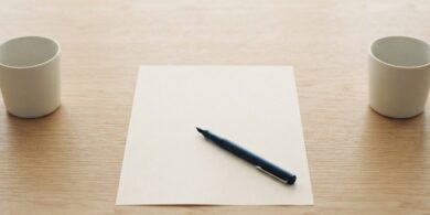 離して置いた2つの無地のカップと、その間の無地の書類とペンの俯瞰イメージ。国際離婚の届出手続を象徴。