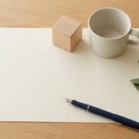 無地の書類の上に木のブロックとカップを並べた俯瞰イメージ。国際養子縁組の手続を象徴。