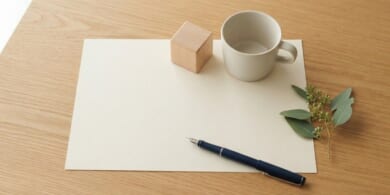 無地の書類の上に木のブロックとカップを並べた俯瞰イメージ。国際養子縁組の手続を象徴。