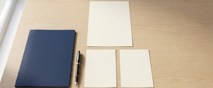 白紙の書類1枚の下に2枚を並べた俯瞰イメージ。特定技能2号が複数の作業員を指導する立場であることを象徴。