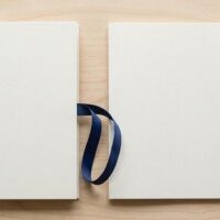 2冊の無地の書類フォルダを紺色のリボンで結んだ俯瞰イメージ。育成就労の二国間協力覚書を象徴。