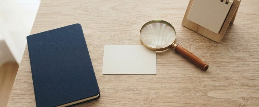 無地のカードと虫眼鏡を並べたイメージ。採用前に在留カードで就労できるかを確認することを象徴。