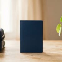 紺色のスーツケースと無地の冊子、観葉植物を置いたイメージ。一時帰国の前の準備を象徴。