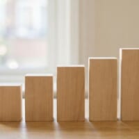 高さが少しずつ増える無地の木製ブロックを並べた机のイメージ。宮崎県の在留外国人の増加を象徴。