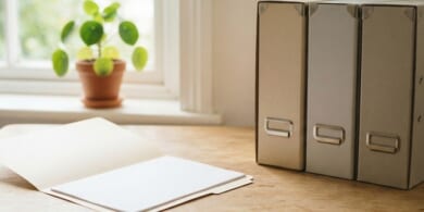 無地の保存箱と開いたファイルを置いた机のイメージ。保管されている過去の記録の取り寄せを象徴。