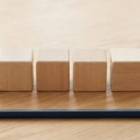 無地の木のキューブ5個を一列に並べ、少し離して6個目を置いた俯瞰イメージ。特定技能1号の通算5年と、6年まで延びる取扱いを象徴。